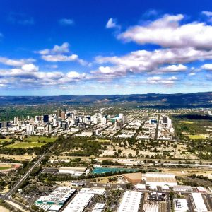 Aerial view of metropolitan Adelaide with city. There is a blue sky in the background with white clouds.