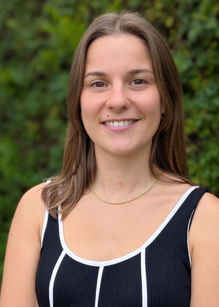 Photo of Natalie, a young woman with medium length brown hair. She is smiling at camera and wearing a sleeveless black top.